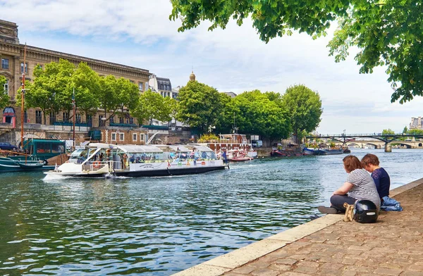 Jóvenes sentados junto al río Sena en la punta de la Isla de la —  Fotos de Stock