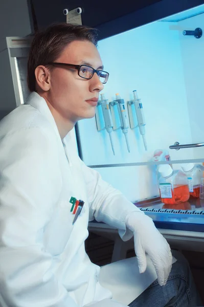 Young male scientist sitting by the cell culture hood — 스톡 사진