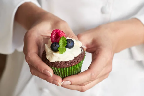 Close-up on hands of female pastry chef with decorated cupcake — Stock Photo, Image