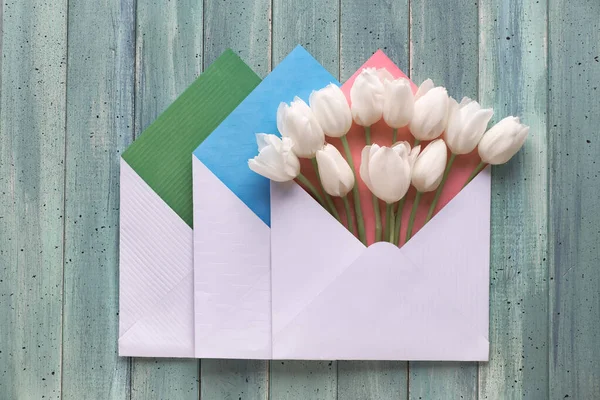 Puesta plana de primavera, tres sobres de papel con tulipanes blancos — Foto de Stock