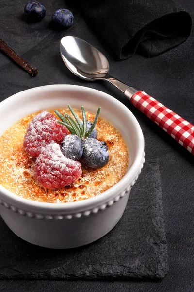 Creme Brulee mit Beeren auf dunklem Stein — Stockfoto