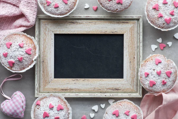Tafel mit zuckerbestreuten Muffins in rosa und weiß Stockbild