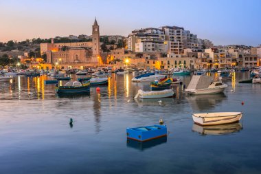Akşamın erken saatlerinde Malta 'nın Marsaskala körfezinde balıkçı ve yolcu botları