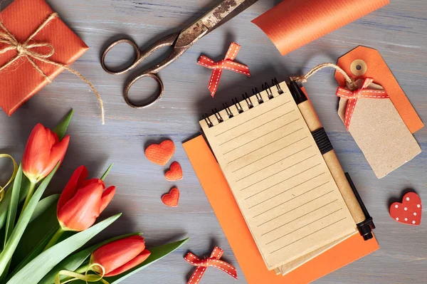 Pusty notatnik, zapakowany prezent, materiały opakowaniowe i świeży pomarańcz — Zdjęcie stockowe