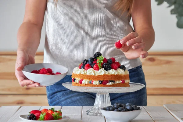 Pastry chef decorates the cake wild berries — Stock Photo, Image