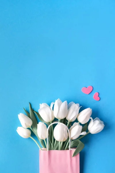 Springtime flat lay, white tulips in paper bag on blue mint back — ストック写真