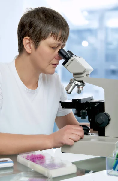 Senior female microscopist in modern laboraboty looks in the mic — Stock fotografie