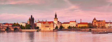 Prag, nehir kenarında gün batımında pembe bir parıltıyla