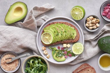 Yeşil salata ve avokado sandviçi, gri taşlı sırt dekoltesinin üst görüntüsü.