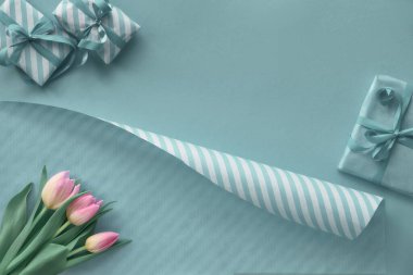 Pembe laleli mavi arka plan, çizgili ambalaj kağıdı ve hediye.