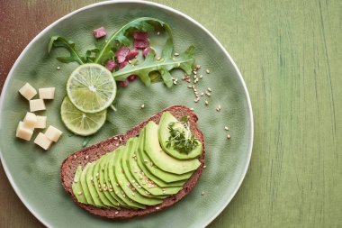 Avokado sandviçi ve yeşil salata ile kahverengi-yeşil t üzerinde jambon küpleri