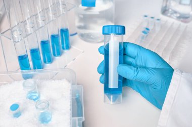 Beyaz ve mavi olarak bilimsel arka plan. Eldiven içinde sıvı örneği
