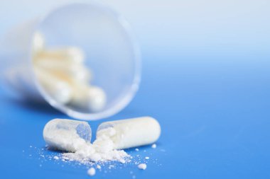 Mavi gradyan üzerinde beyaz toz ile bölünmüş şeffaf kapsül