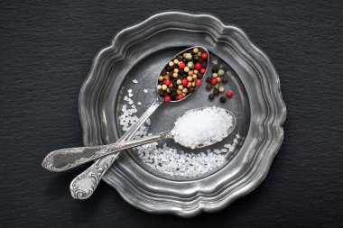 Eski metal tabakta eski kaşıklarda karışık biberli tuz.