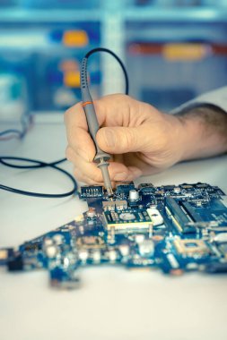Closeup elektronik panosuna donanım tamir dükkanı. Sığ DOF, el odaklanmak ve test aracı, sizin metin için yer. Bu görüntü tonda.