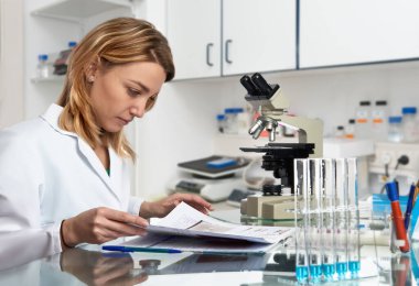 Genç Avrupalı kadın bilim adamı laboratuvar günlüğünü kontrol ediyor