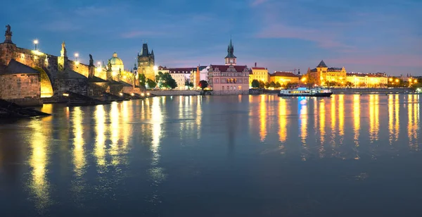 Panoramatický obraz osvětleného Karlova mostu se odráží ve Vltavě — Stock fotografie