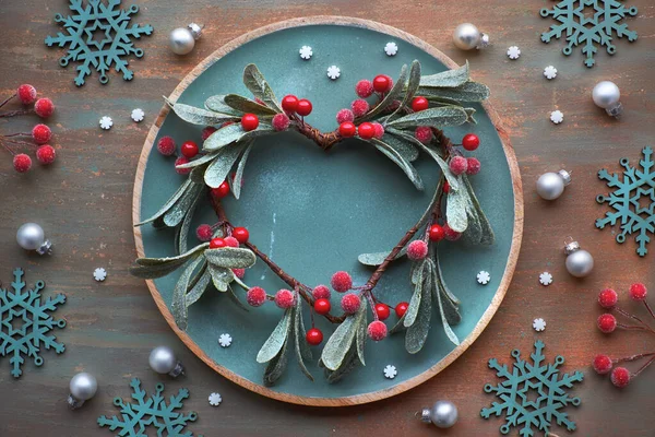 Red mistletoe Christmas wreath on round decorative tray on dark — Stock Photo, Image