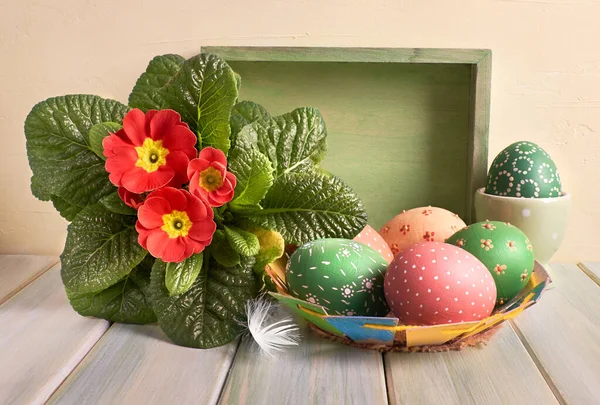 Пасхальная корзина с окрашенными пасхальными яйцами и красным горшком — стоковое фото
