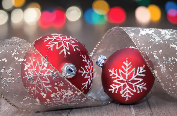 Två röda julgranskulor och färgglada ljus — Stockfoto
