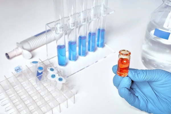 Próbka cieczy w ręce samicy, niebieskie próbki cieczy w probówkach szklanych — Zdjęcie stockowe