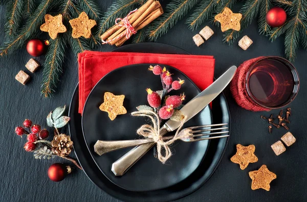 Black plates and vintage cutlery with Christmas decorations — Stock Photo, Image