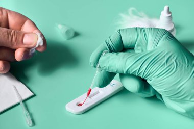 İgm ve IgG antikorları için COVID-19 testi yapın. Yeni Coronavirus SARS-CoV-2, Covid-19. Eldivenli hemşire Coronavirus testine kan uygular. Hasta parmakları önde, yeşil nane arkaplanı..