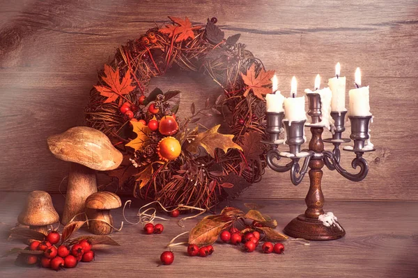 Natural Fall Thanksgiving harvest. Autumn leaves, vintage candle stick with burning candles, decorative wreath, berry and wooden mushrooms. Eco friendly zero waste decor. Autumn rustic decorations