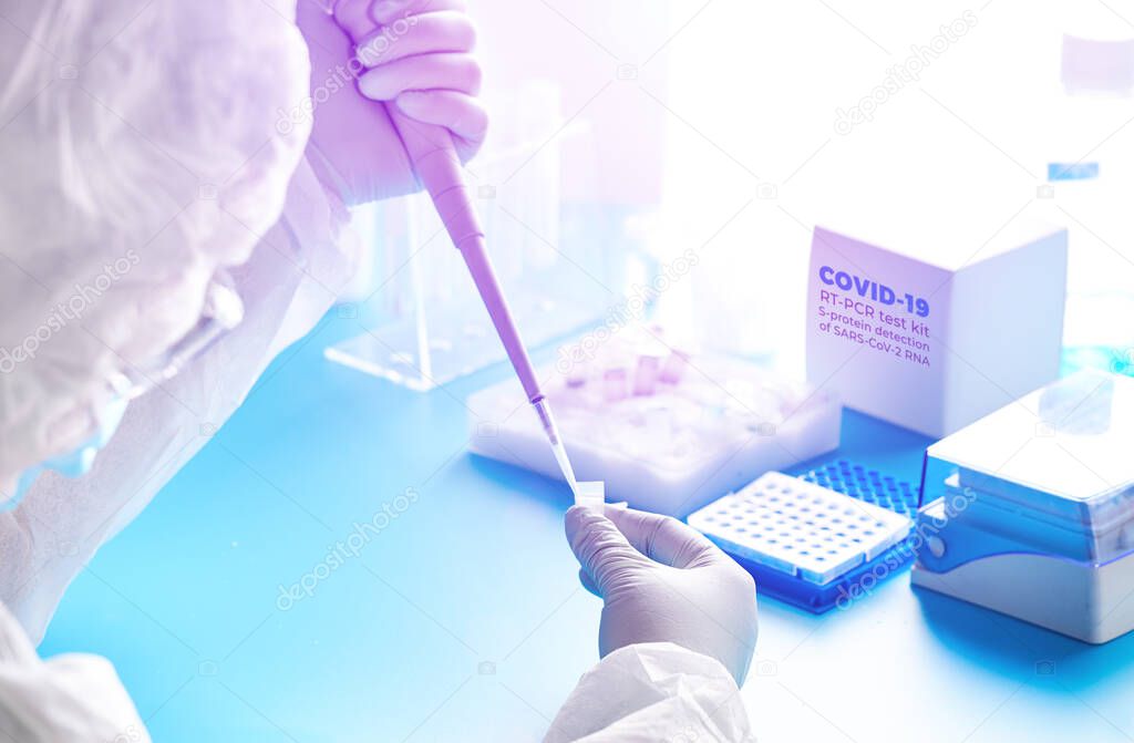 SARS-COV-2 pcr diagnostics concept. Epidemiologist in protective suit, mask and glasses works with patient swabs to detect 2019-nCoV virus causing Covid-19 viral pneumonia.