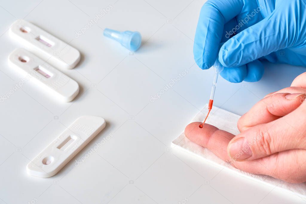 Rapid COVID-19 test for detection of specific antibodies IgM and IgG to novel corona virus SARS-CoV-2 causing Covid-19 illness. Medic or doctor collects blood from patient finger, closeup on hands.