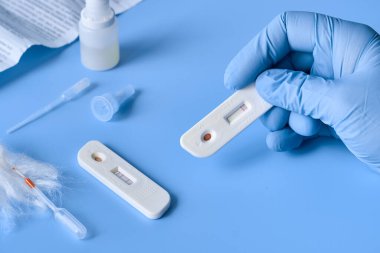 İgm ve IgG antikorları için COVID-19 testi yapın. Yeni Coronavirus SARS-CoV-2, Covid-19. Eldivenli hemşire hasta kanını tek kullanımlık pipetle topluyor. Mor naneli mavi neon arkaplan.