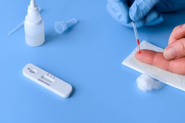 İgm ve IgG antikorları için COVID-19 testi yapın. Yeni Coronavirus SARS-CoV-2, Covid-19. Eldivendeki sıhhiyeciler hastanın kanını tek kullanımlık pipetle topluyor. Canlı mavi veya mor arkaplan.