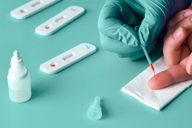 İgm ve IgG antikorları için COVID-19 testi yapın. Yeni Coronavirus SARS-CoV-2, Covid-19. Nitril eldivenli hemşire hasta kanını tek kullanımlık pipetle topluyor. Gren naneli turkuaz arkaplan.