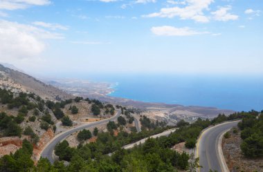 Tepeden kıyı yoluna ve Girit 'in kıyı şeridine bakın. Suyun üzerindeki sisli bir günde, sakin denizin üzerindeki ufku kaplıyor..