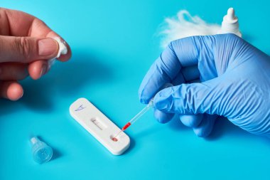 İgm ve IgG antikoronavirüs SARS-CoV-2, Covid-19 viral zatürree için hızlı COVID-19 testi. Eldivenli sıhhiyeciler testi durdurur. Canlı mavi nane ve turkuaz renkler.