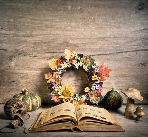 Autumn rustic decorations and open vintage old book. Natural Fall Thanksgiving, harvest concept. Autumn leaves, decorative wreath, berry, pumpkins.
