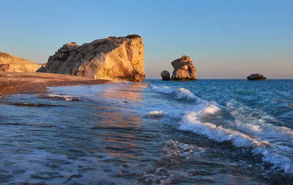 Aphrodite rock Cyprus in soft evening light, curvy waves in the foreground touristic attraction of so called love rock