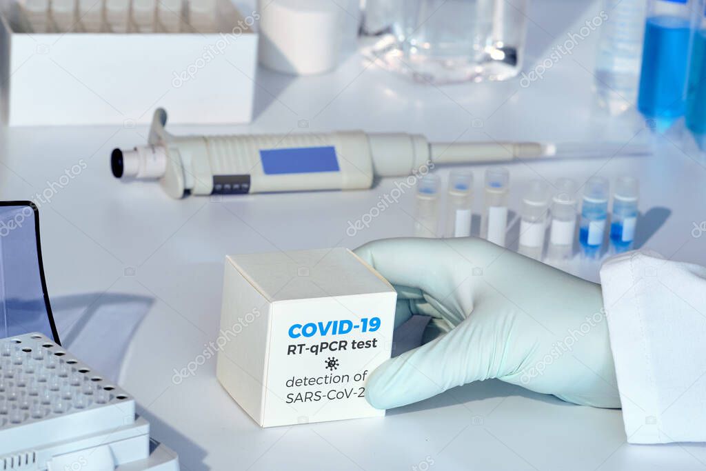 Quick novel COVID-19 coronavirus test kit. SARS-CoV-2 pcr diagnostics kit. Hand in glove with the box. The kit detects covid19 illness.