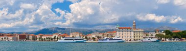Split City Limanı 'nın panoramik görüntüsü. Deniz, yolcu gemileri, tarihi evler, arkasında dağlar olan kule.