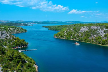 Sibenik Köprüsü 'nden Adriyatik Denizi' ne doğru Krka Nehri kanyonu manzarası. Skradin kasabasının aşağısında, Kuzey Dalmaçya, Hırvatistan. Sahil şeridi resmi, kuş bakışı, bulutlu gökyüzü..