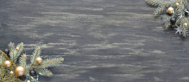 Noel arkaplanı, koyu ahşap desenli panoramik üst görünüm. Köşe süsleri, süslenmiş köknar dalları, beyaz ve gri cam oyuncaklar, yıldızlar, ıvır zıvırlar. Metin ve kopyalama alanı için boşluk.