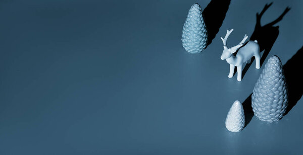 Модная изометрическая рождественская композиция с керамическим оленем и рождественскими елками в голубом. Двухцветный монохромный бумажный фон, панорамный дизайн баннера с копировальным пространством