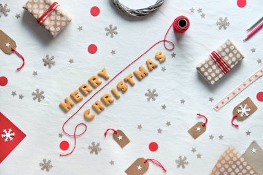 Kurabiye mektuplarından yapılmış Mutlu Noeller mesajı. Yaratıcı Xmas dairesi hediye kutuları ve el sanatları kağıdından yapılmış dekorlarıyla yatıyordu. Geometrik arkaplan, sıfır atık çevre dostu, plastiksiz kendi kendine yapılmış dekorasyon.