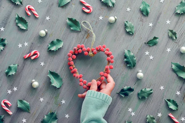 Coroa Coração Mão Segurando Decorado Com Bagas Foscas Fundo Natal — Fotografia de Stock
