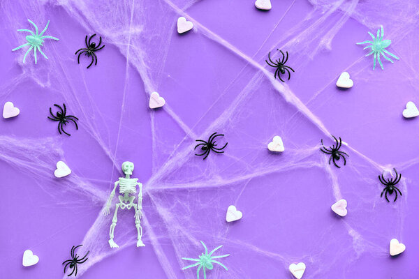 Творческий Хэллоуин фон с белым сахарным сердцем, паутина, пауки и декоративные скелеты на ярко-фиолетовой неоновой бумаге. Плоский, вид сверху, триумфальный фон.