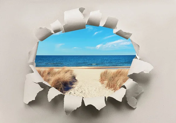 Paper hole with image of deserted beach on Baltic sea with grass on dunes and sea.. Last minute offer, discount. Reopening of Northerner Europe, vacations after quarantine.