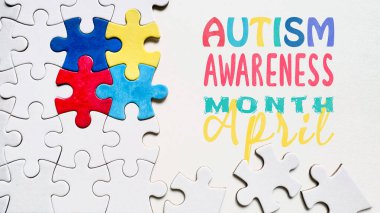 Autism Awareness Month April concept featuring colorful puzzle pieces on a white background with text 