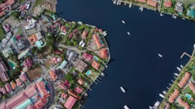 İnsansız hava aracı liman manzarasını yatlar, çatılar, havuzlar, arabalı bir yol ve deniz kıyısı (Rodney Bay, Saint Lucia) ile kaldırır.)