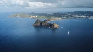 Bir yatın kıyıdaki bir dağı pas geçtiği gibi bir hava aracı havalanıyor, diğer yatlar denizde, bir şehirdeki bir adada duruyor (Rodney Bay, Saint Lucia)