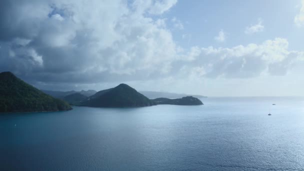 空中カメラは青空の下でヨットで青い海の丘陵海岸に近づきます セントルシア — ストック動画